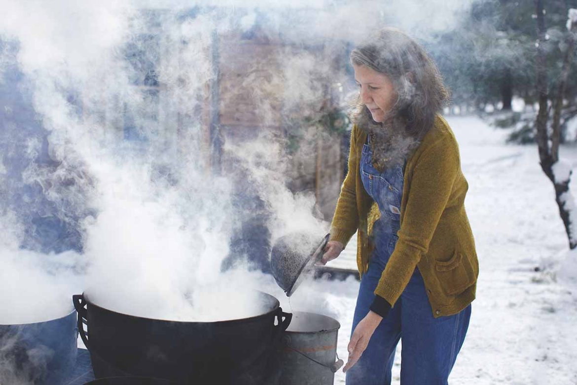 woman cooking in big pot with steam