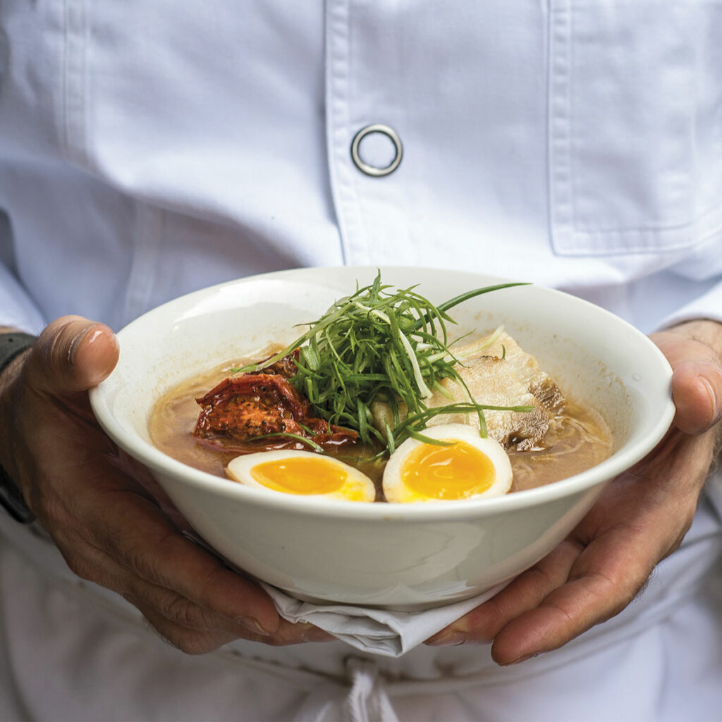 bowl of ramen with soft-boiled egg in two hands