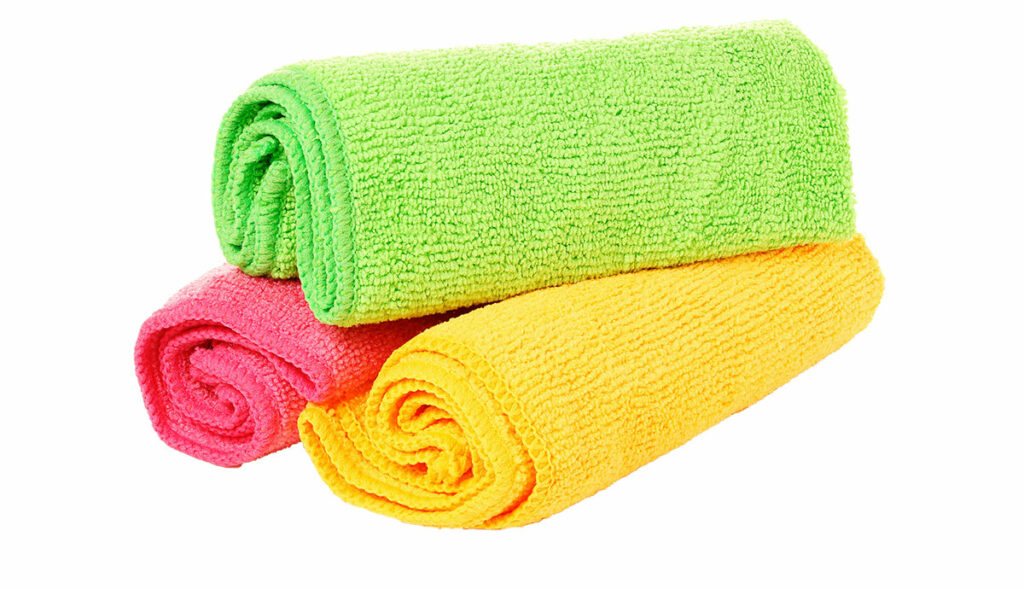 three microfiber cloths in green, pink, and yellow, stacked in a triangle