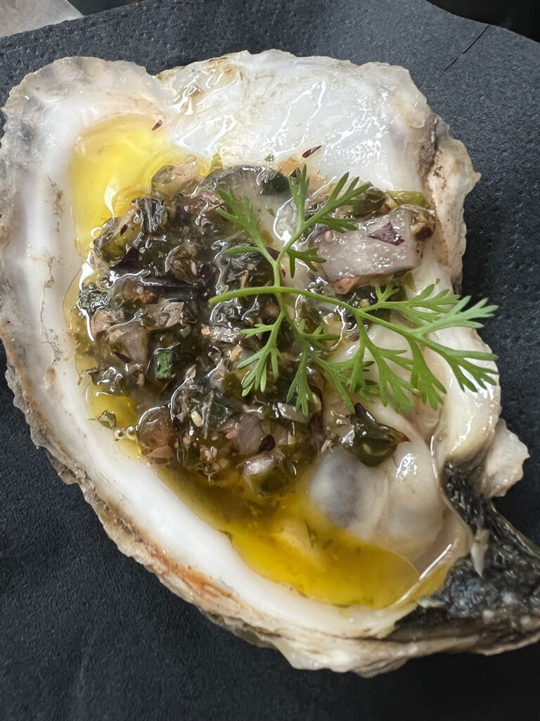 close-up of raw oyster with seaweed gremolata on top