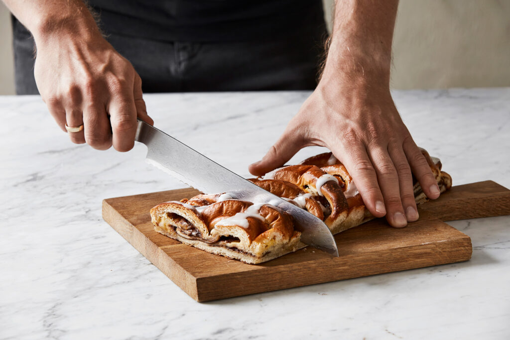 hands cutting a cinnamon social on a wooden cutting board