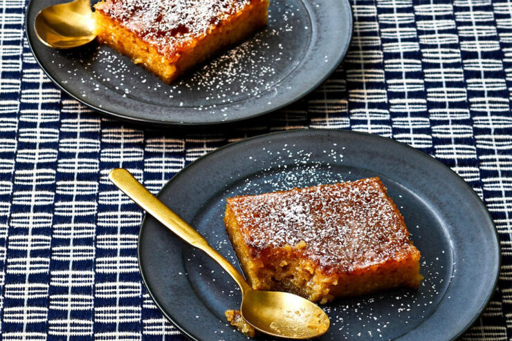 malva pudding on deep blue-grey plates with gold spoons