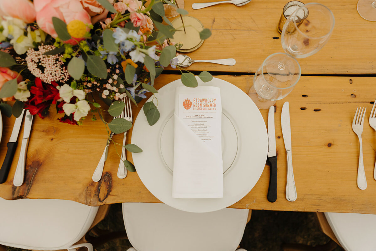 a place setting on a wooden table accented with flowers