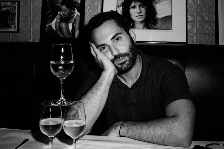 black and white portrait of chef andy baraghani with three wine glasses stacked on table
