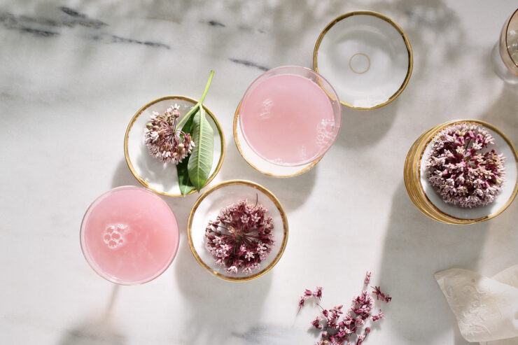 white and gold cups containing milkweed blossoms and a homemade milkweed elixer