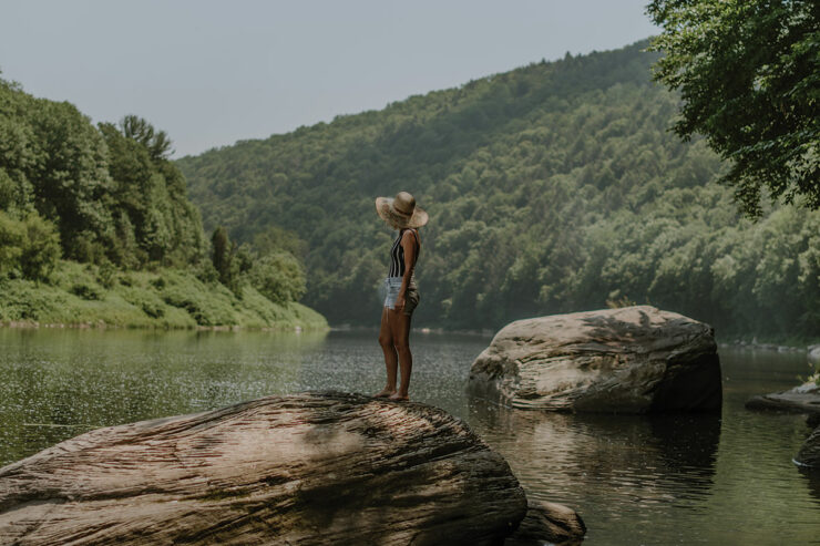 woman with straw hat looking out at lake and mountains