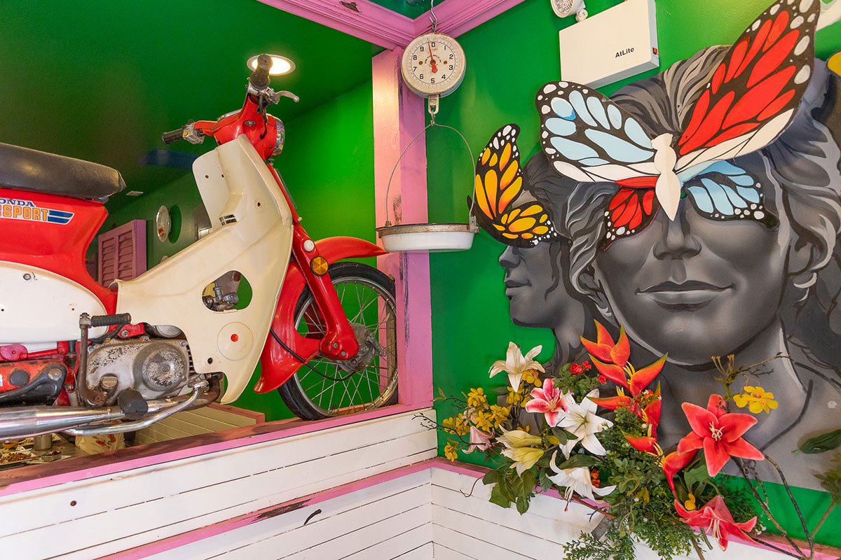 a colorful mural on a restaurant wall with a classic moped scooter on display nearby