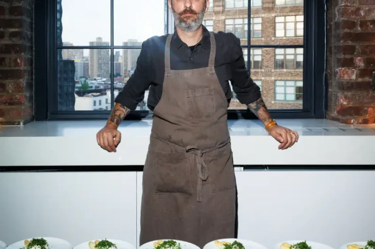 Chef Nick Curtola of Four Horsemen and I Cavallini stands before plates of food at the Edible Schoolyard NYC fundraiser