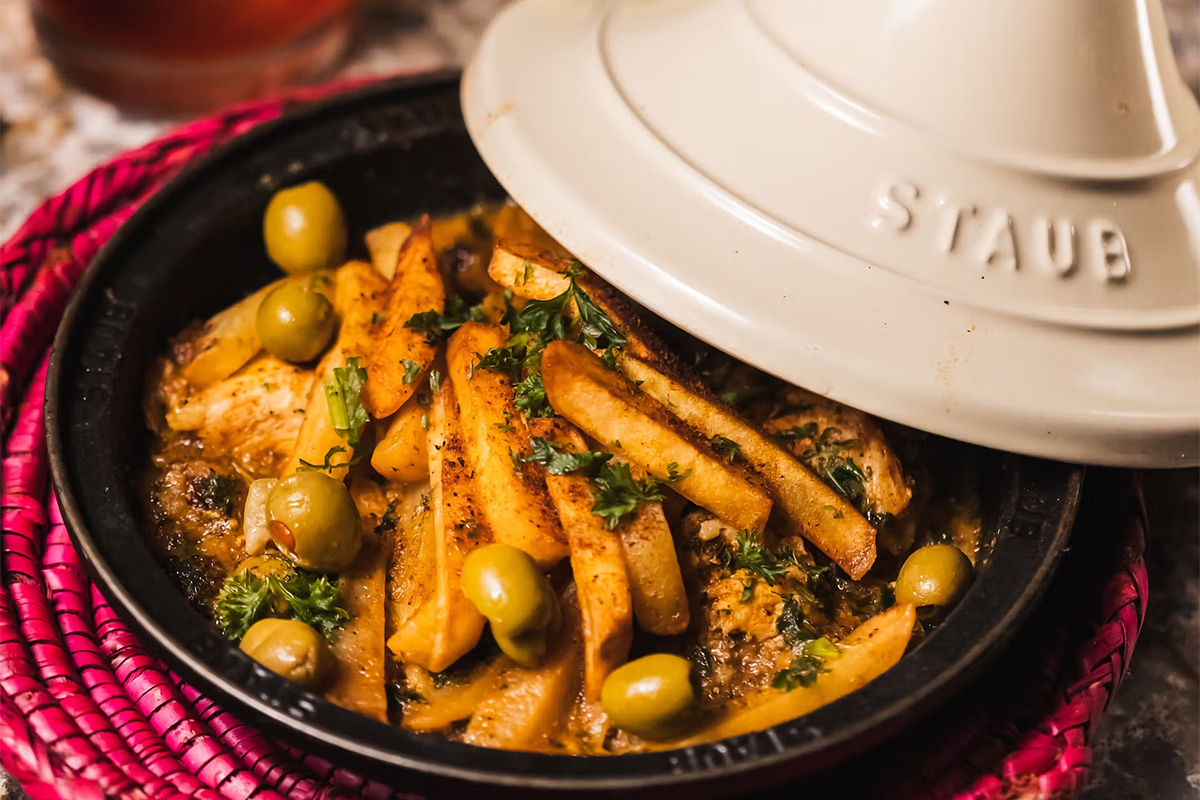 a crock pot dish with french fries and olives